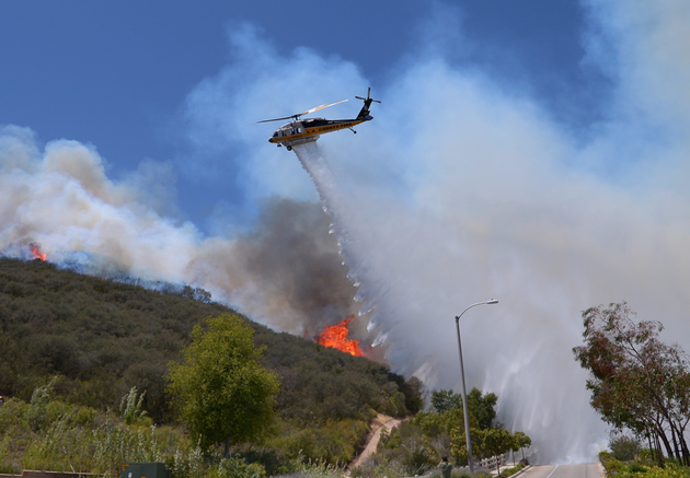 A helicopter makes a water drop on flames as a wildfire burns along a hillside in Thousand Oaks, Calif., Thursday, May 2, 2013. A Ventura County Fire Department spokeswoman said the blaze that broke out Thursday morning near Camarillo and Thousand Oaks, 50 miles west of Los Angeles, had spread to over 6,500 acres, forcing evacuations of nearby neighborhoods. (AP Photo/Mark J. Terrill)