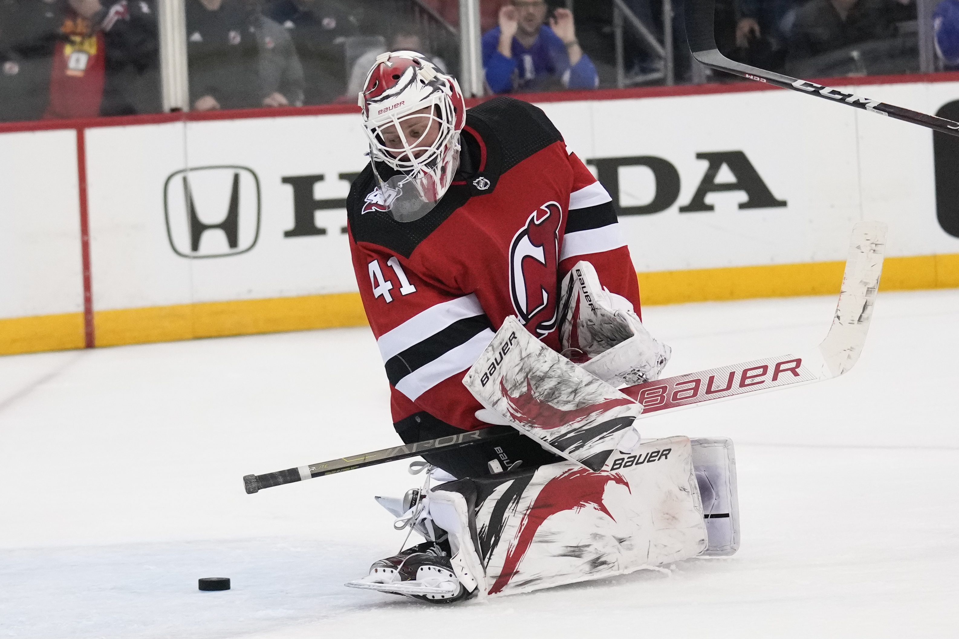 New Jersey Devils goaltender Akira Schmid, back, makes a glove save as  defenseman Dougie Hamilton watches during the third period of the team's  NHL hockey game against the Colorado Avalanche on Wednesday
